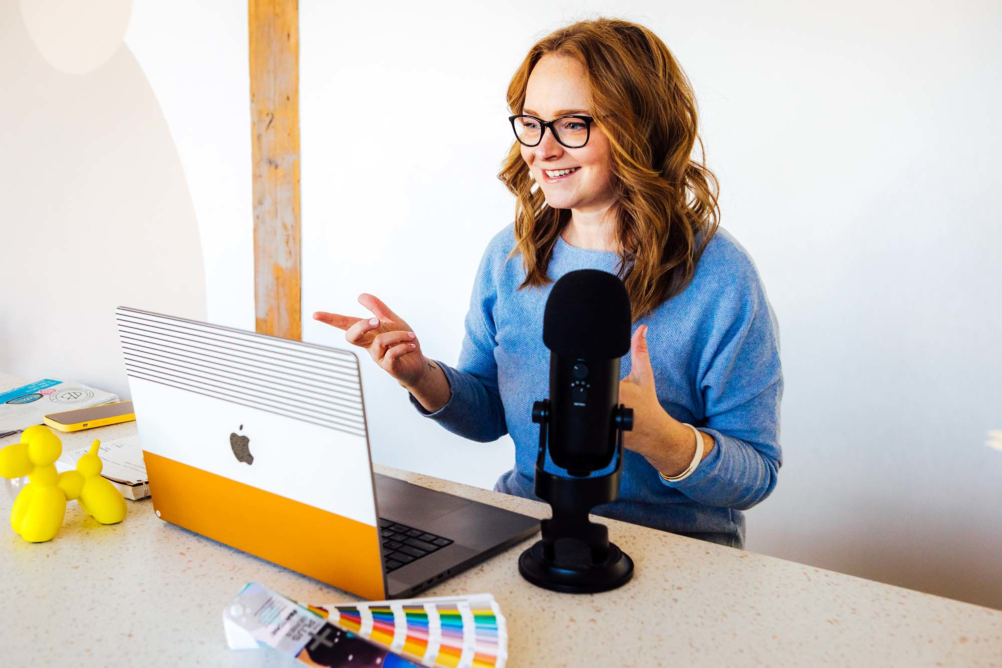 HeartSpark founder Lauren Atherton takes an online meeting on her laptop, with a podcast mic in front of her.