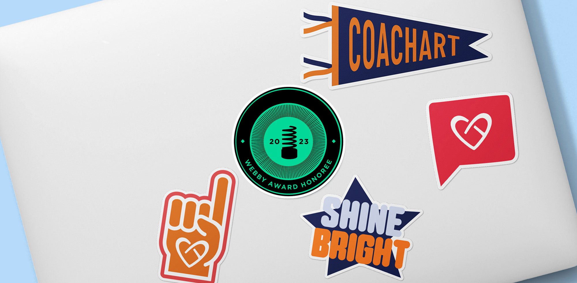 Silver laptop covered in CoachArt stickers, plus a bright green sticker for a 2023 Webby Honoree Award.