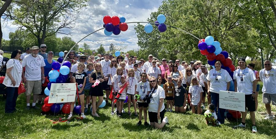 A large group of people gathered under a balloon arch for The Marfan Foundation's first Walk for Victory event in Denver, Colorado.